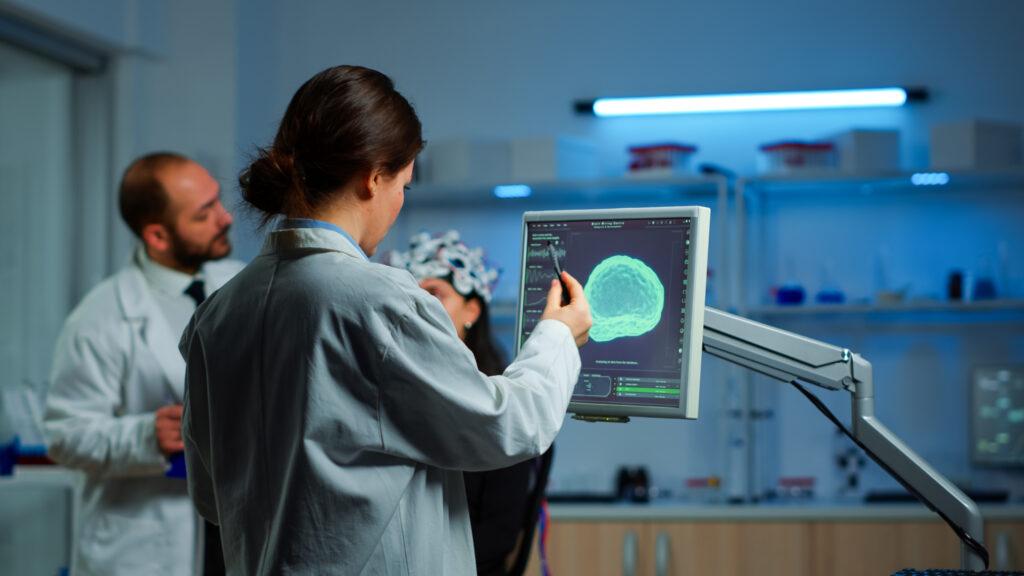 researcher looking monitor analysing brain scan while coworker discussing with patient background about side effects mind functions nervous system tomography scan working laboratory